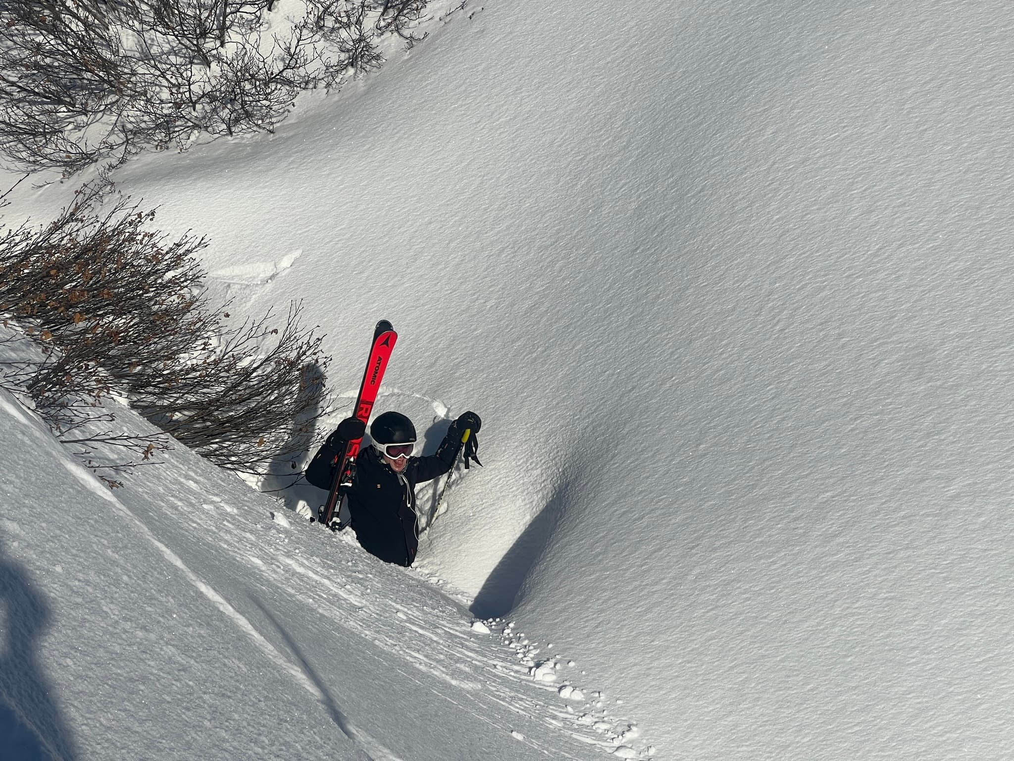 Felix, waist-deep in powder snow, holding up his skis
